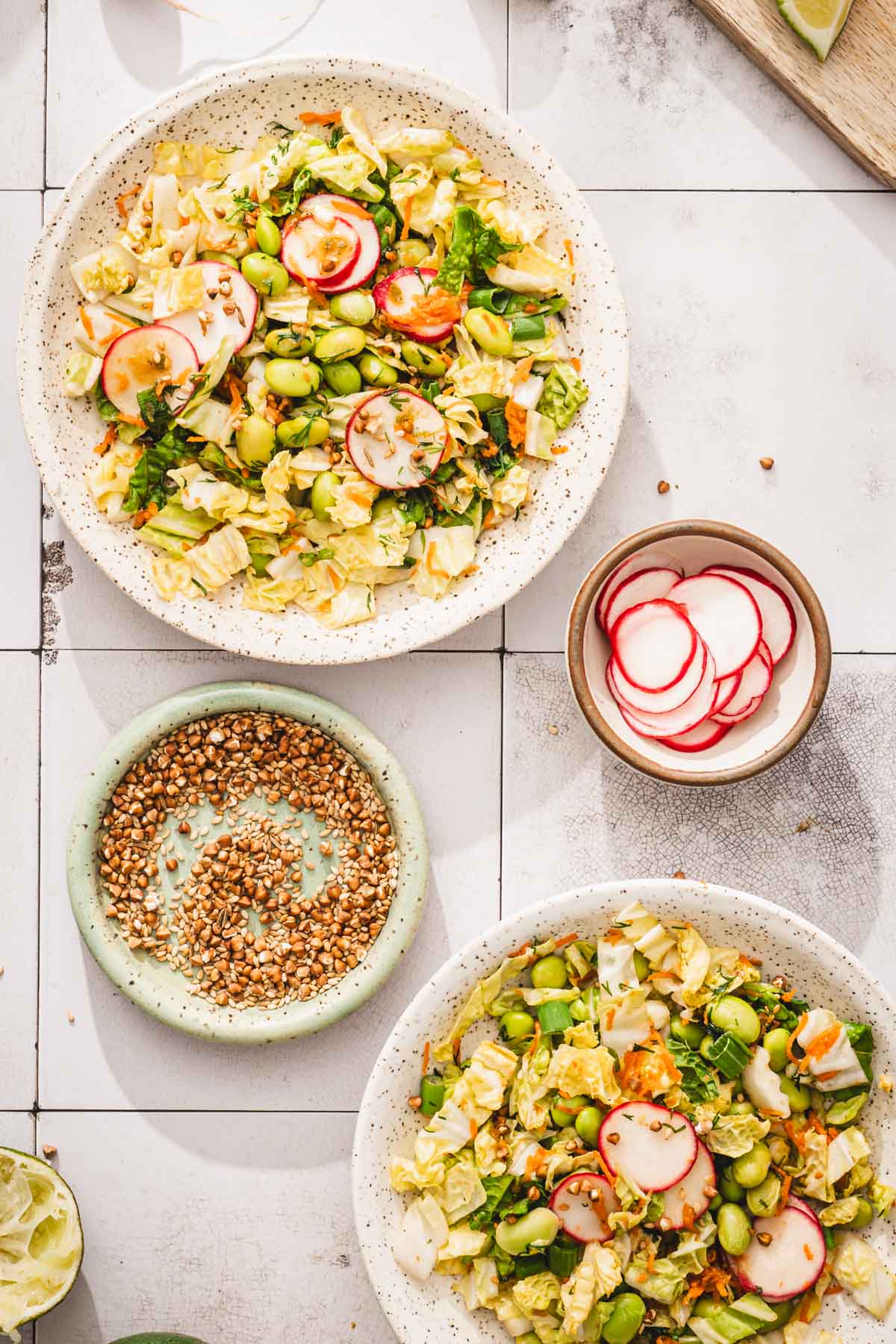 various bowls with the napa cabbage salad, small dish with roasted topping and pickled radishes
