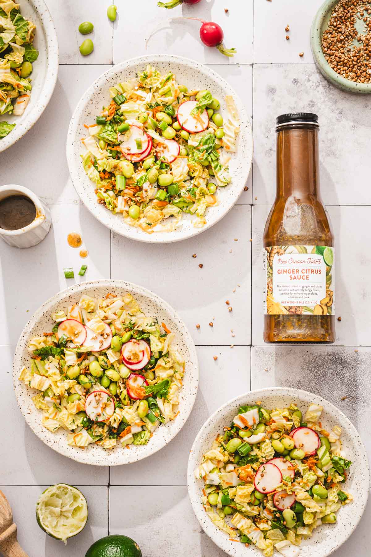various bowls with the napa cabbage salad, bottle with brand dressing