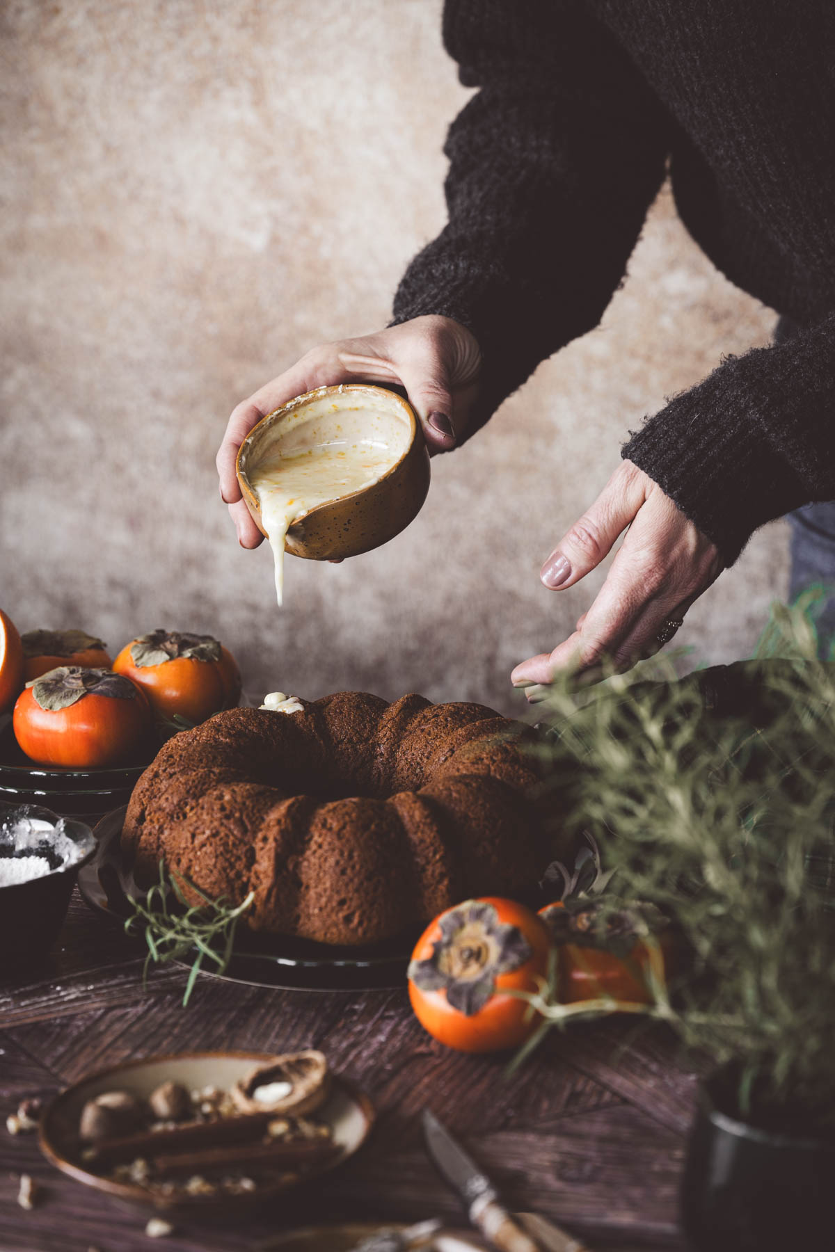 hands in frmae pouring glaze over the cake
