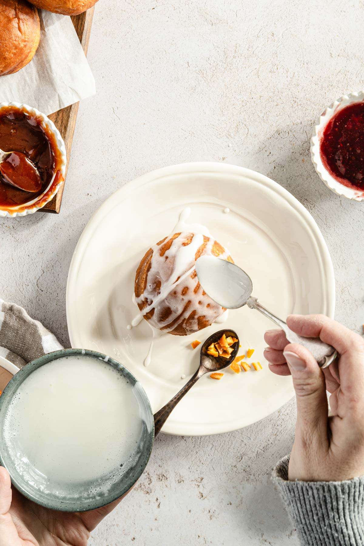 hands in frame applying sugar glaze to paczki