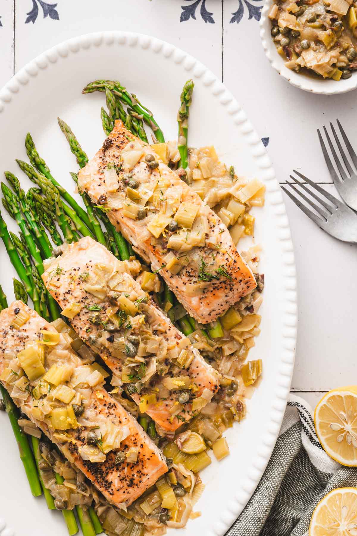 salmon served over asparagus on a white platter