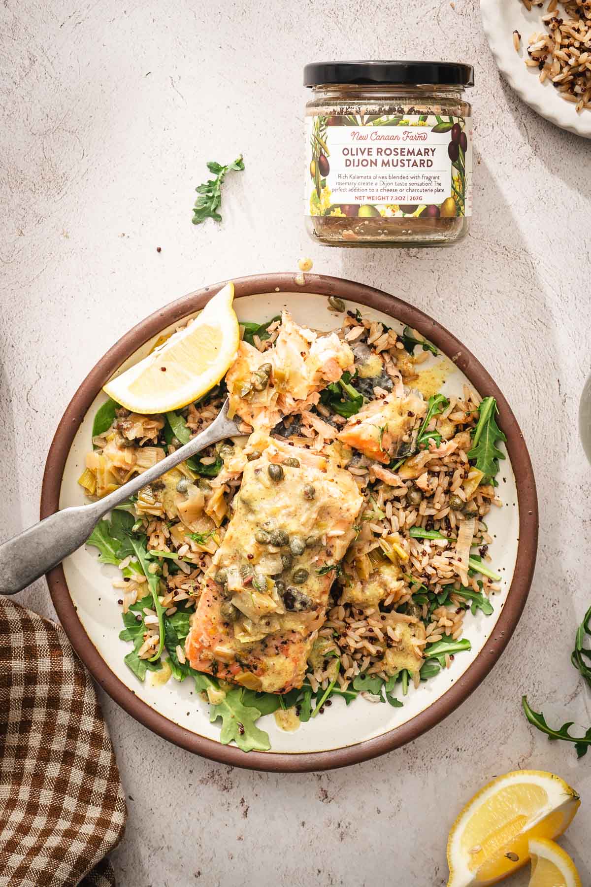 plate with salmon over salad and rice, jar with mustard