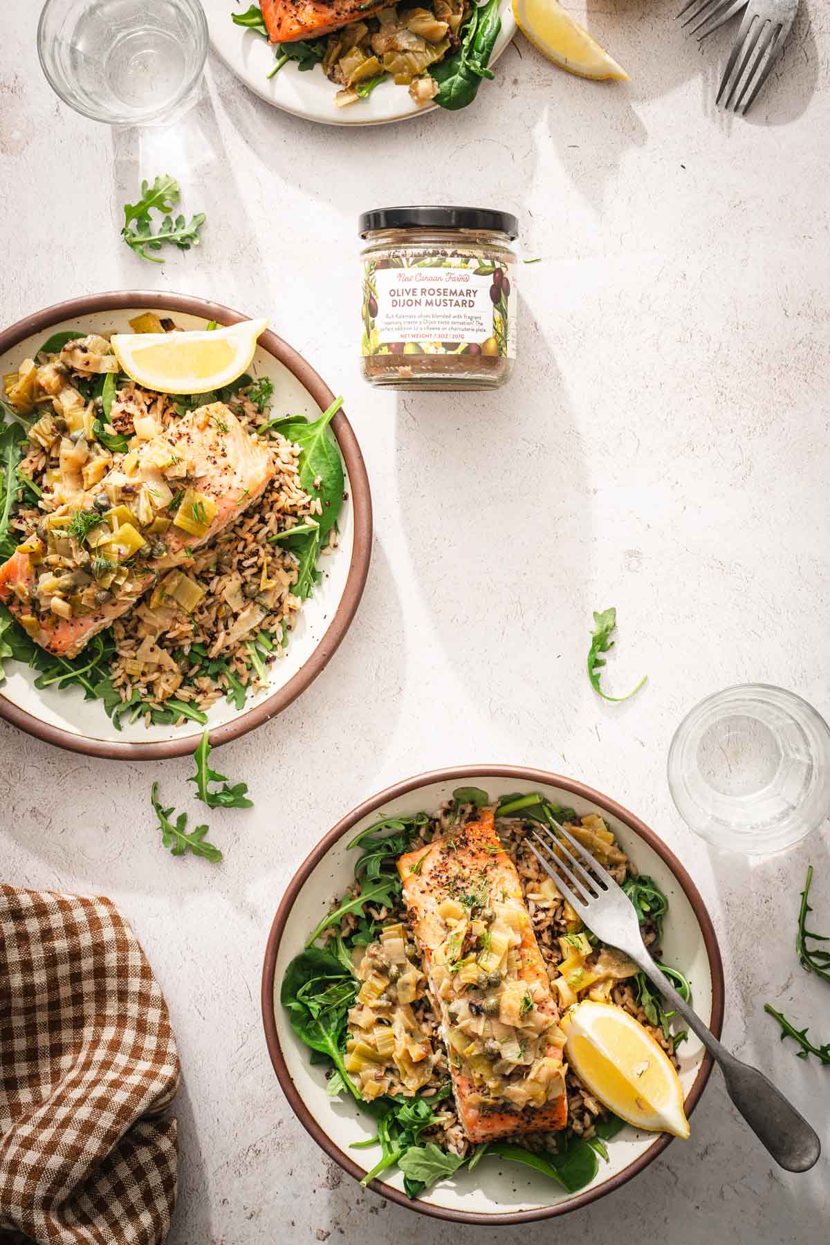 various plates with salmon, napkin, jar with mustard