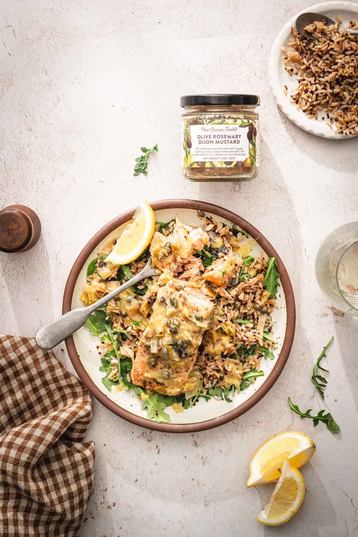 plate with green salad, grains and seared salmon, jar with mustard