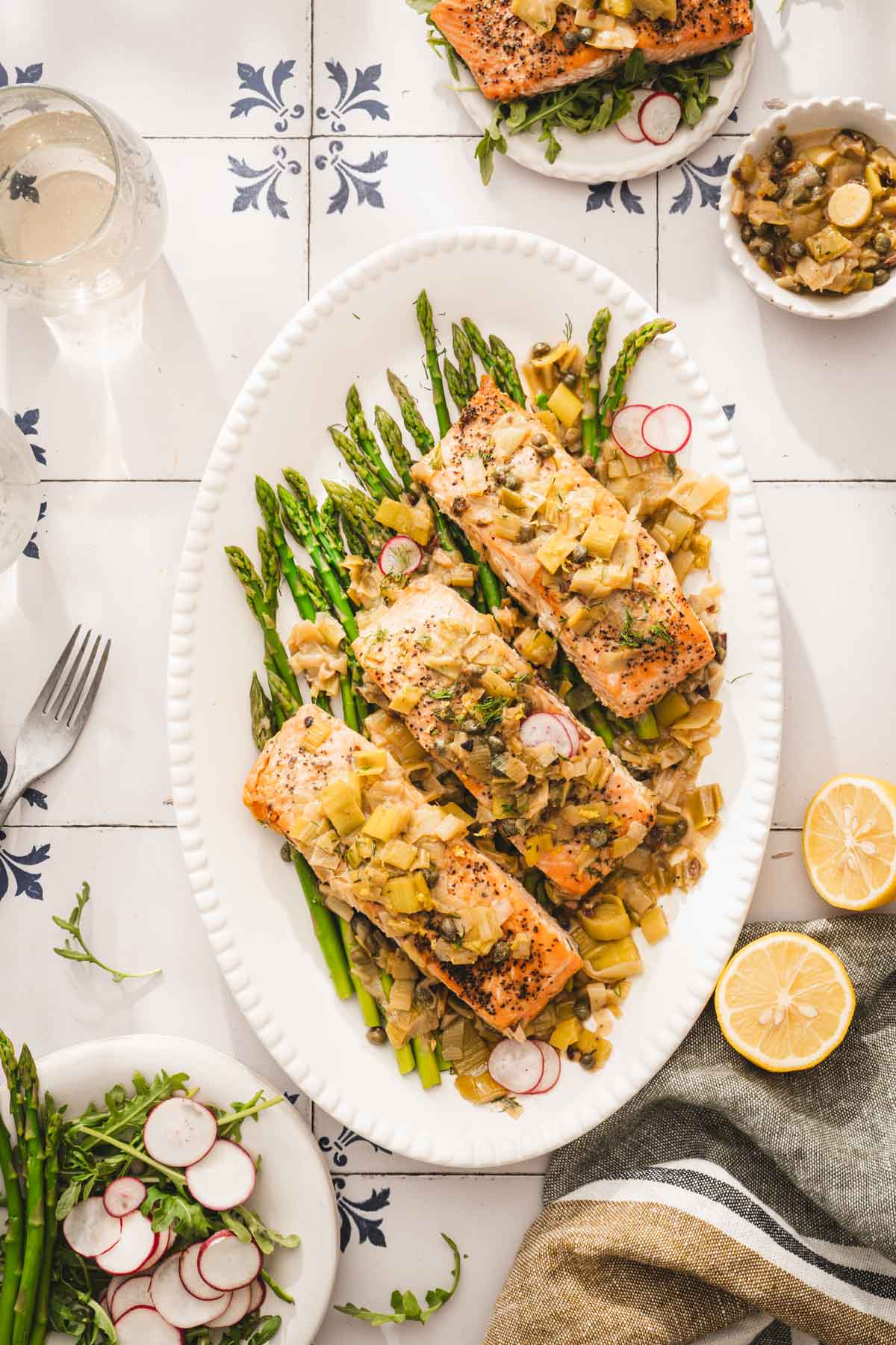 salmon on a serving platter, other plates around, glasses with wine