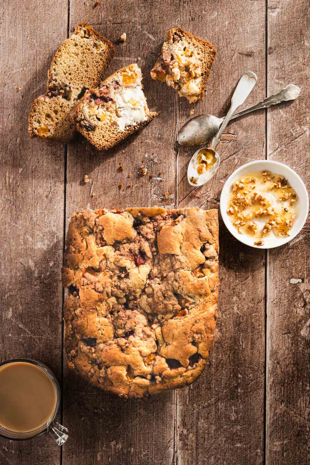 peach bread sliced, dish with honey, small knife, cup of coffee, top view