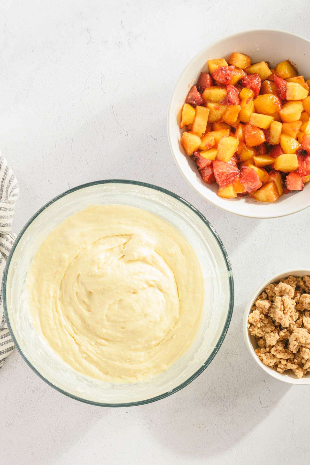 bowl with bread batter (wet and dry ingredients mixed in), bowl with peaches and one with crumble