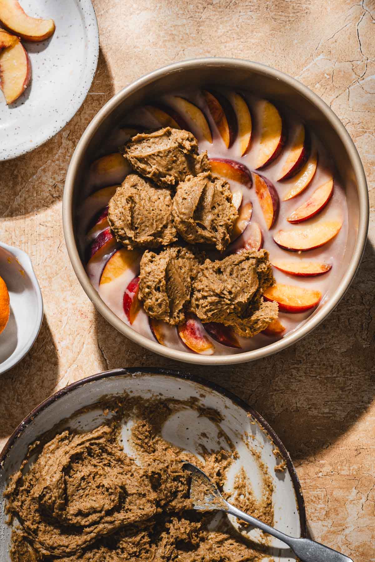 baking pan with arranged peaches with some batter added