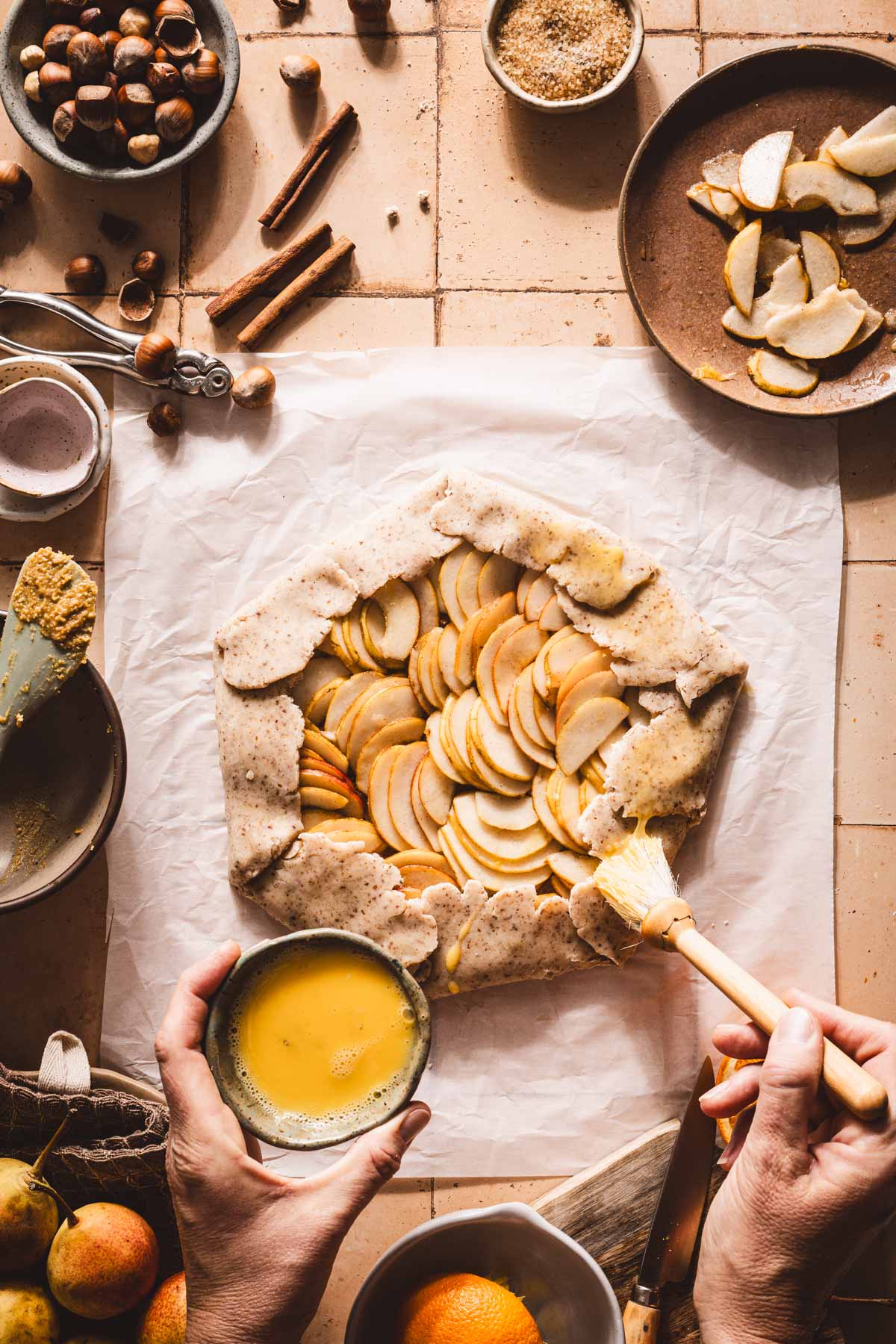 hands in frame applying egg wash to the edges of the dough