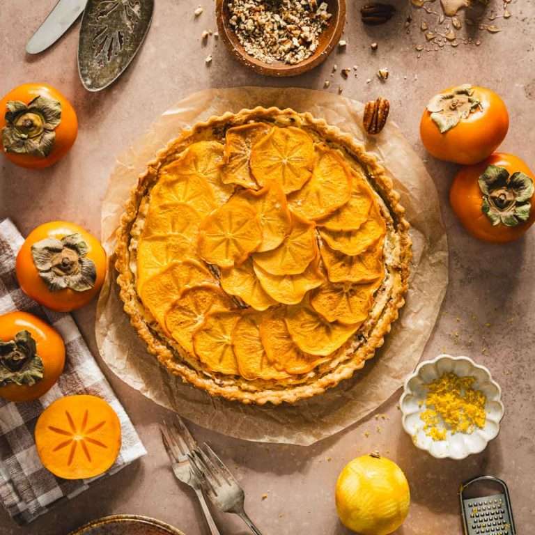 baked persimmon tart , bowl with crushed nuts, fresh persimmons, lemons and zest