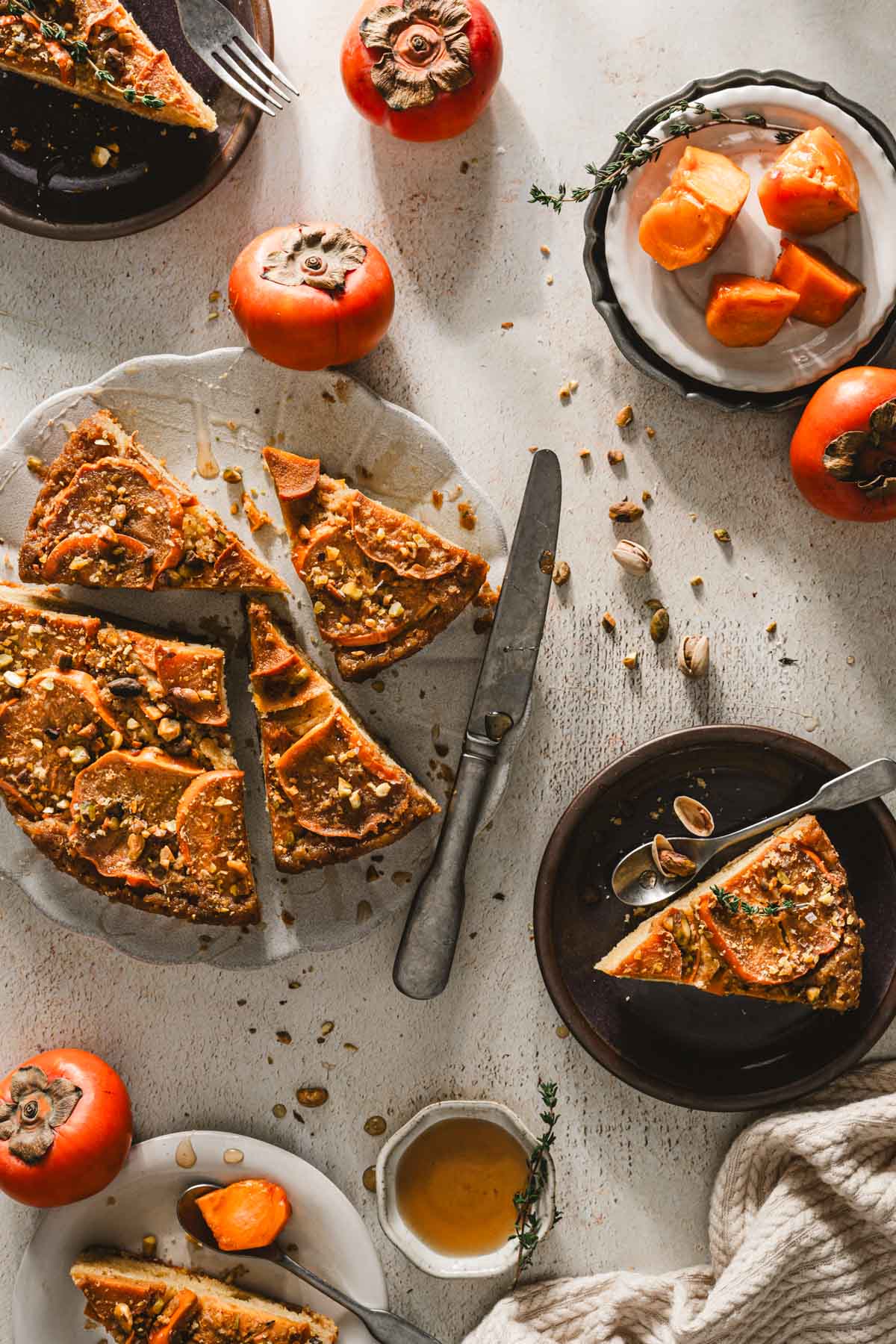white background, persimmon cake on a serving plate, other small plates around