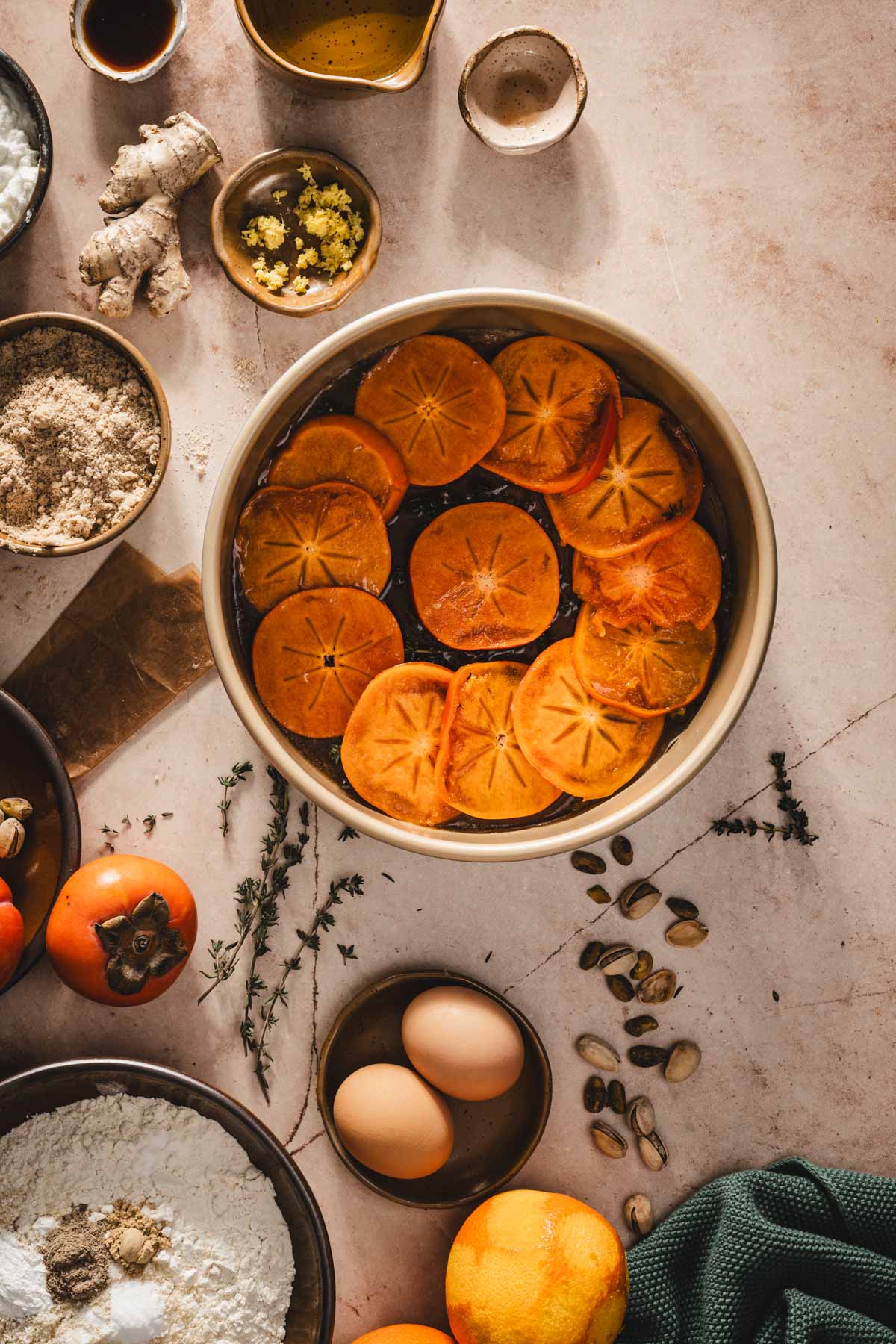 slices of persimmons arranged over the caramel layer