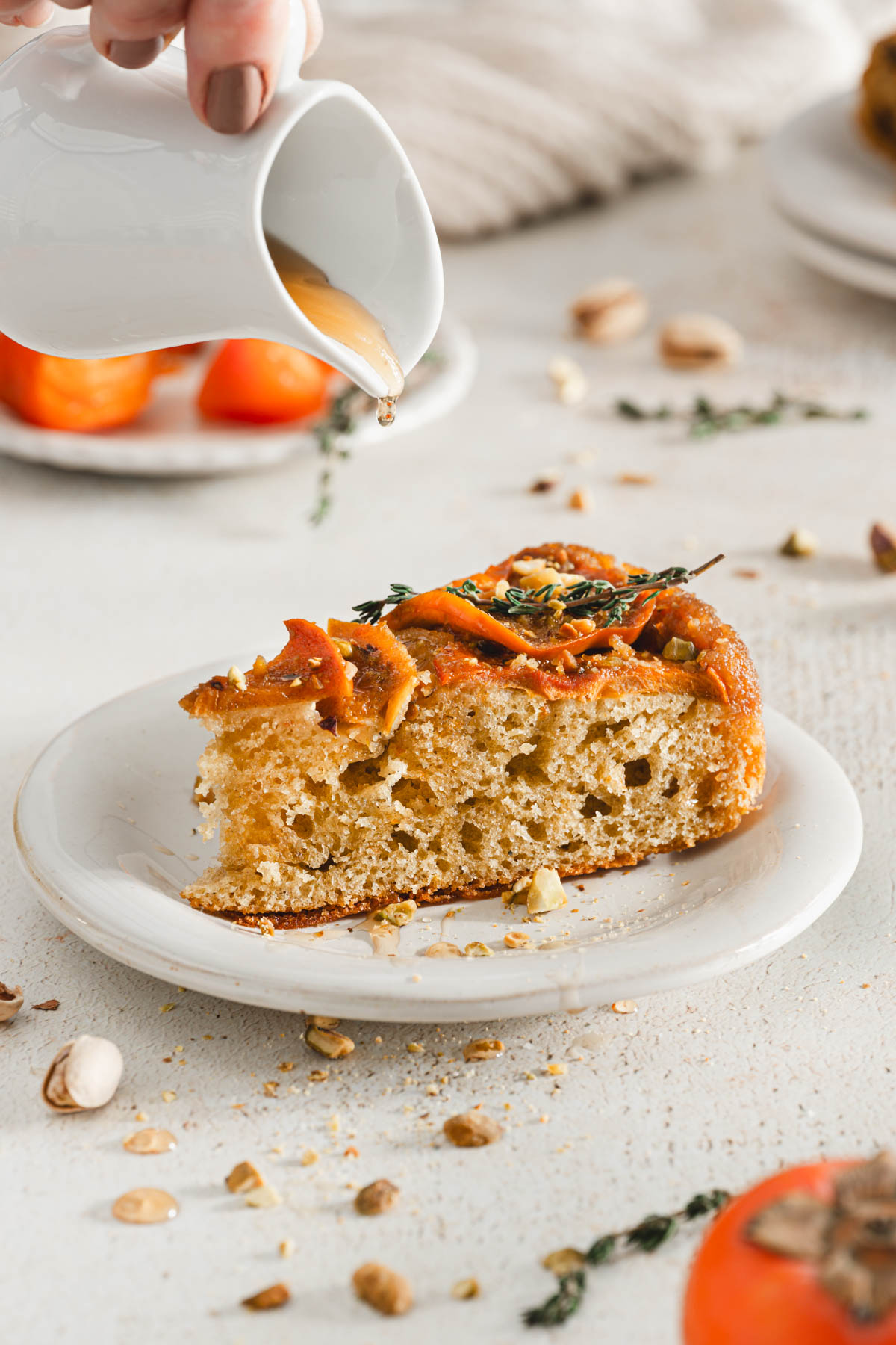 front view of a slice of cake on a plate, little pourer with syrop