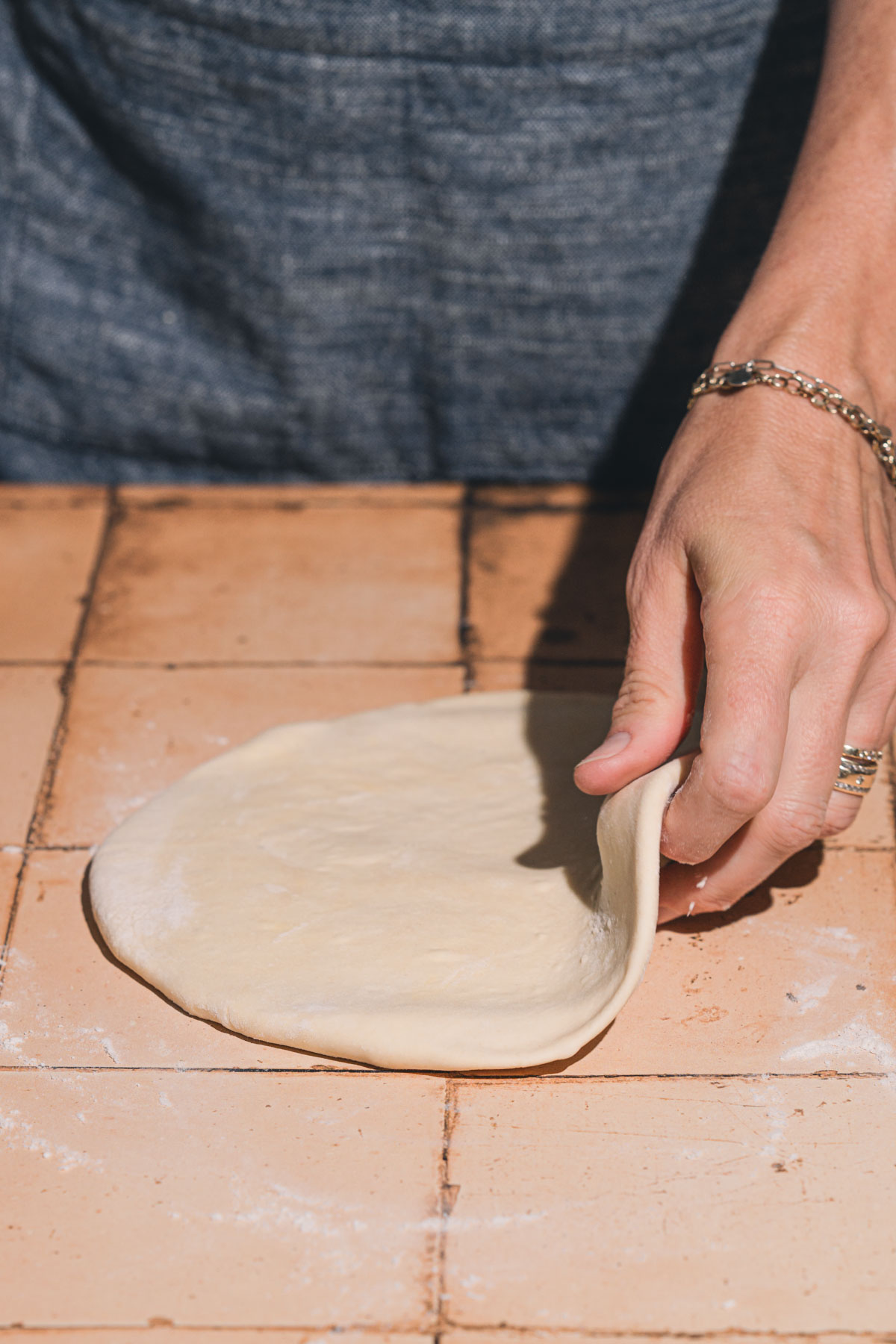 hands in frame holding piece of the rolled out dough