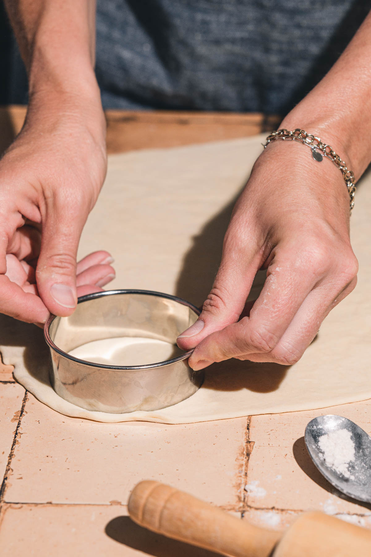 hands in frame holding a cookie cutter over pierogi dough