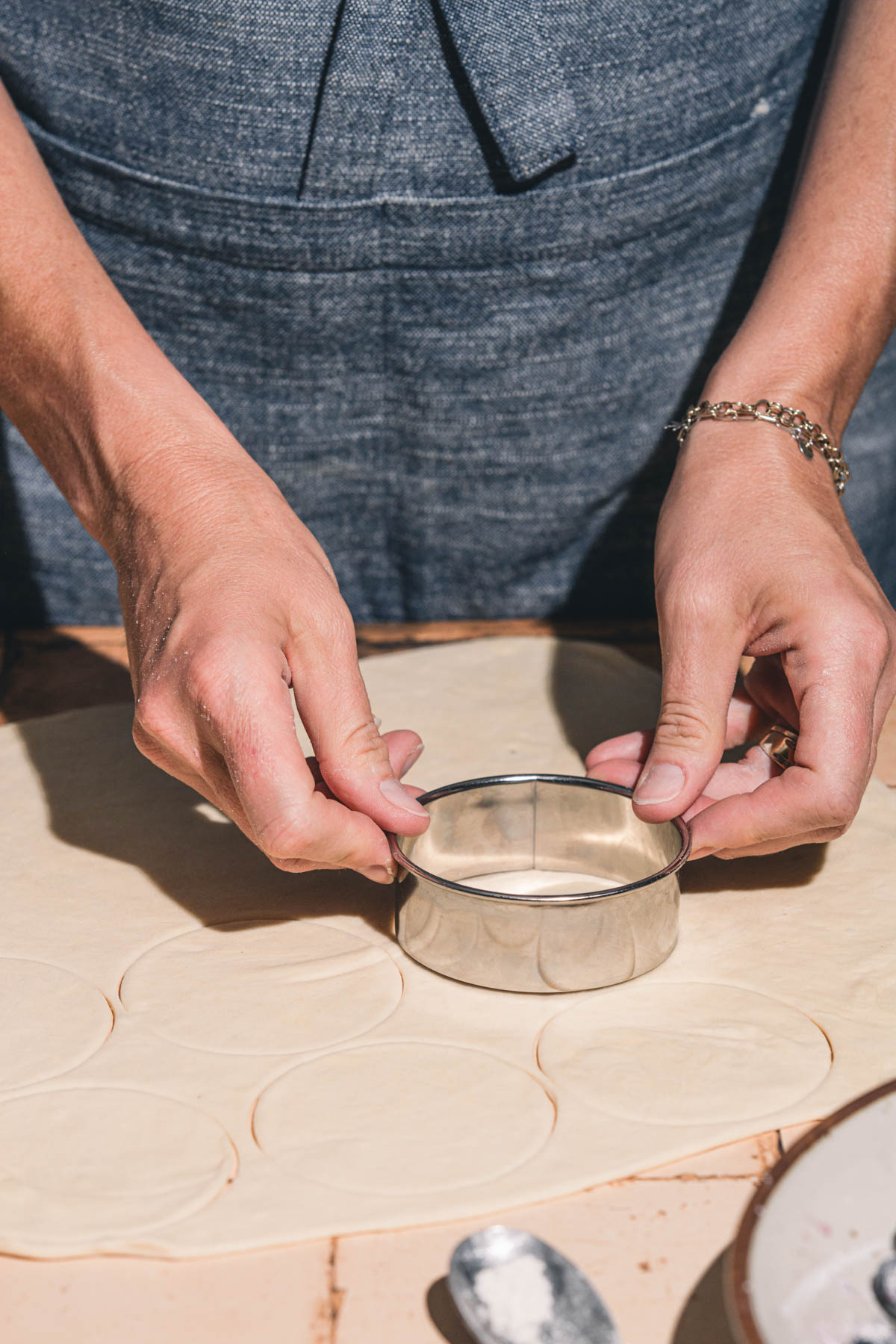 hands in frame holding a cookie cutter over pierogi dough