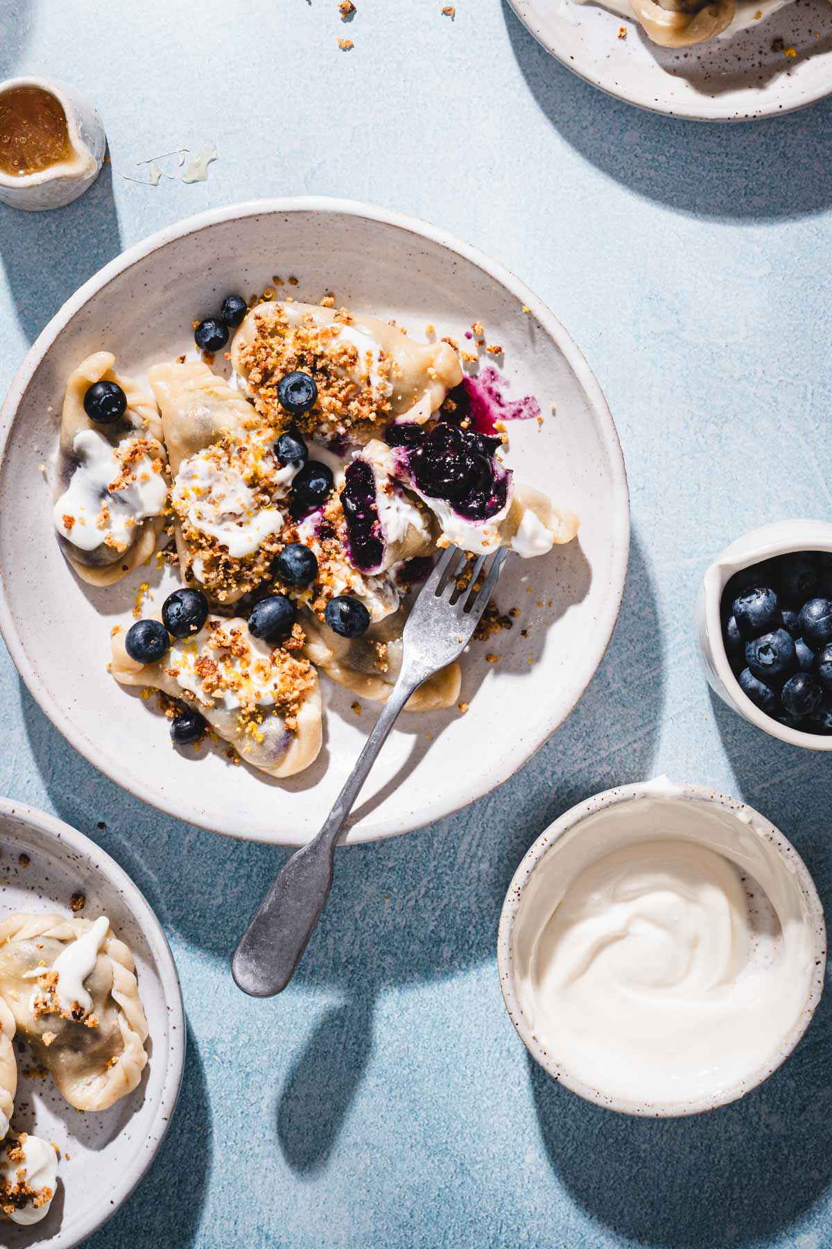 plates with piergoi, dish with cream, blueberries, honey