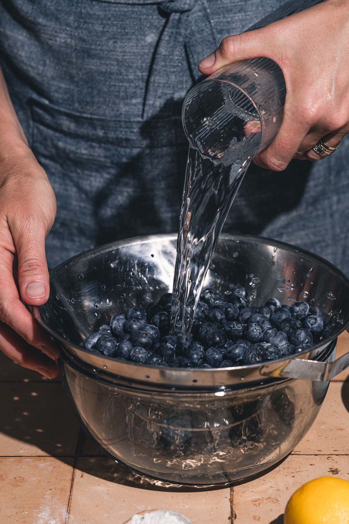hands in frame pouring water over blueberries