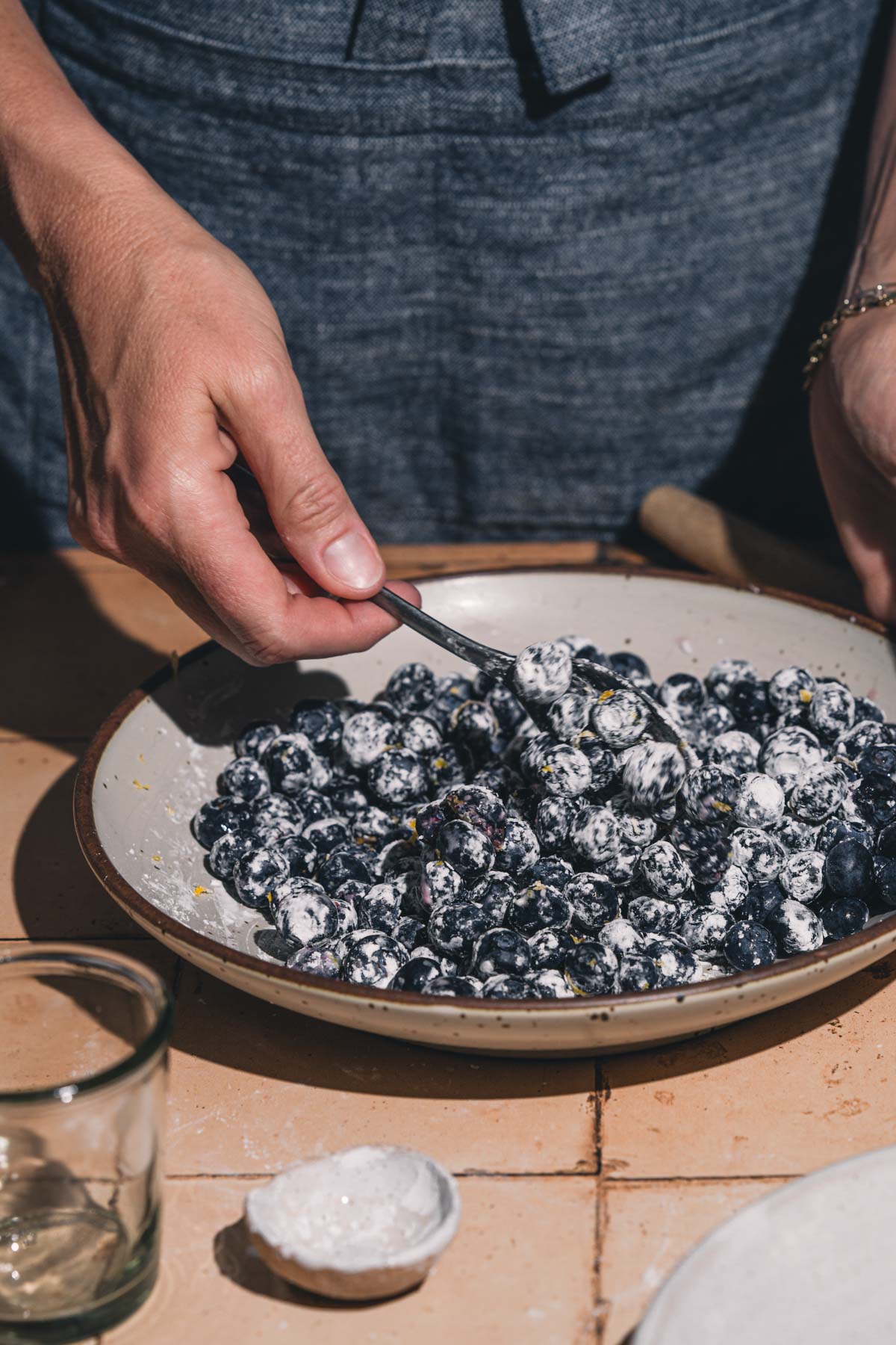 hands in frame mixing blueberries with cornstarch