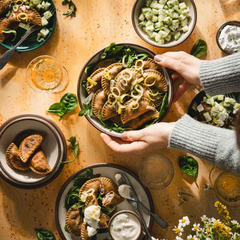hands holding bowl with pierogi