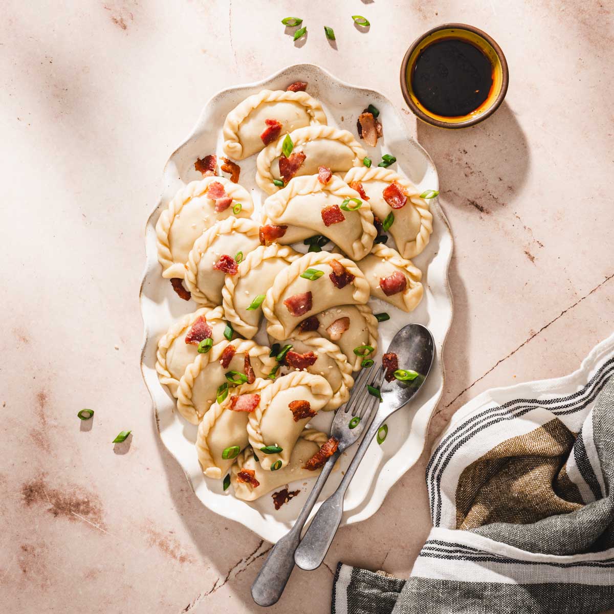 pierogi on a serving platter, dish with dipping sauce