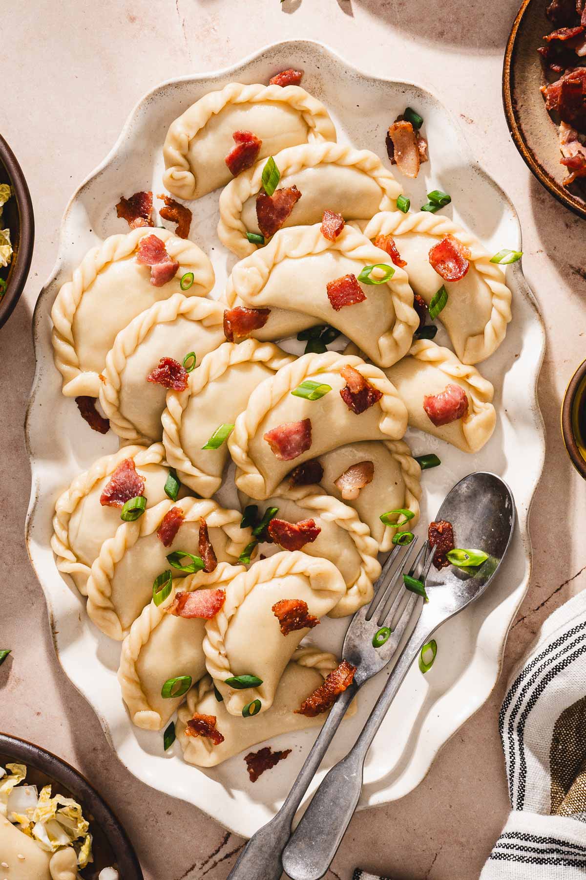 top view,c lose up of pirogi on a platter, garnishd with bacon and green onions