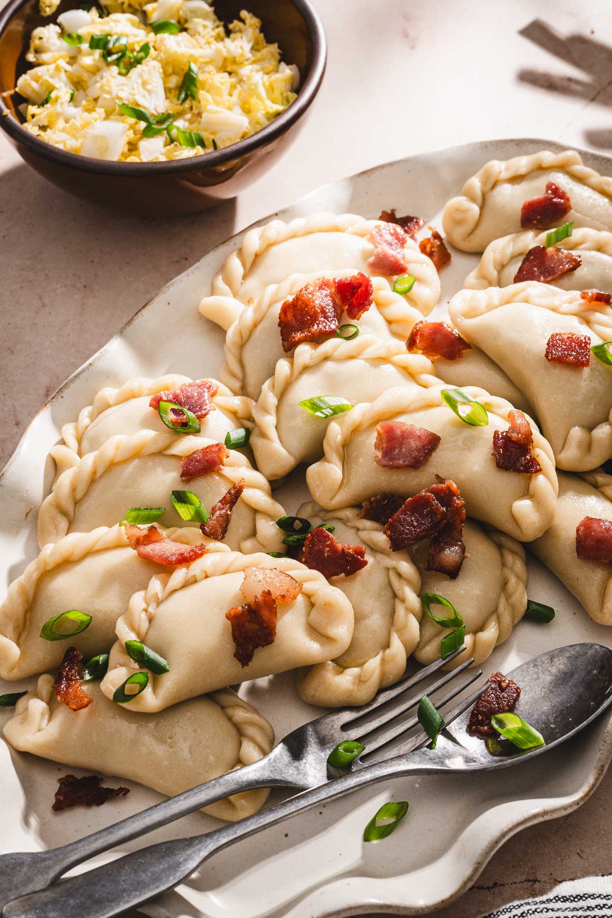 sid view of pierogi garnishd with bacon and gren onions