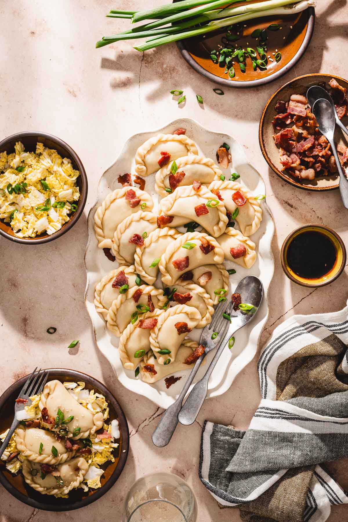 top viw of pireogi on a serving platter, garnished with bacon and gren onions