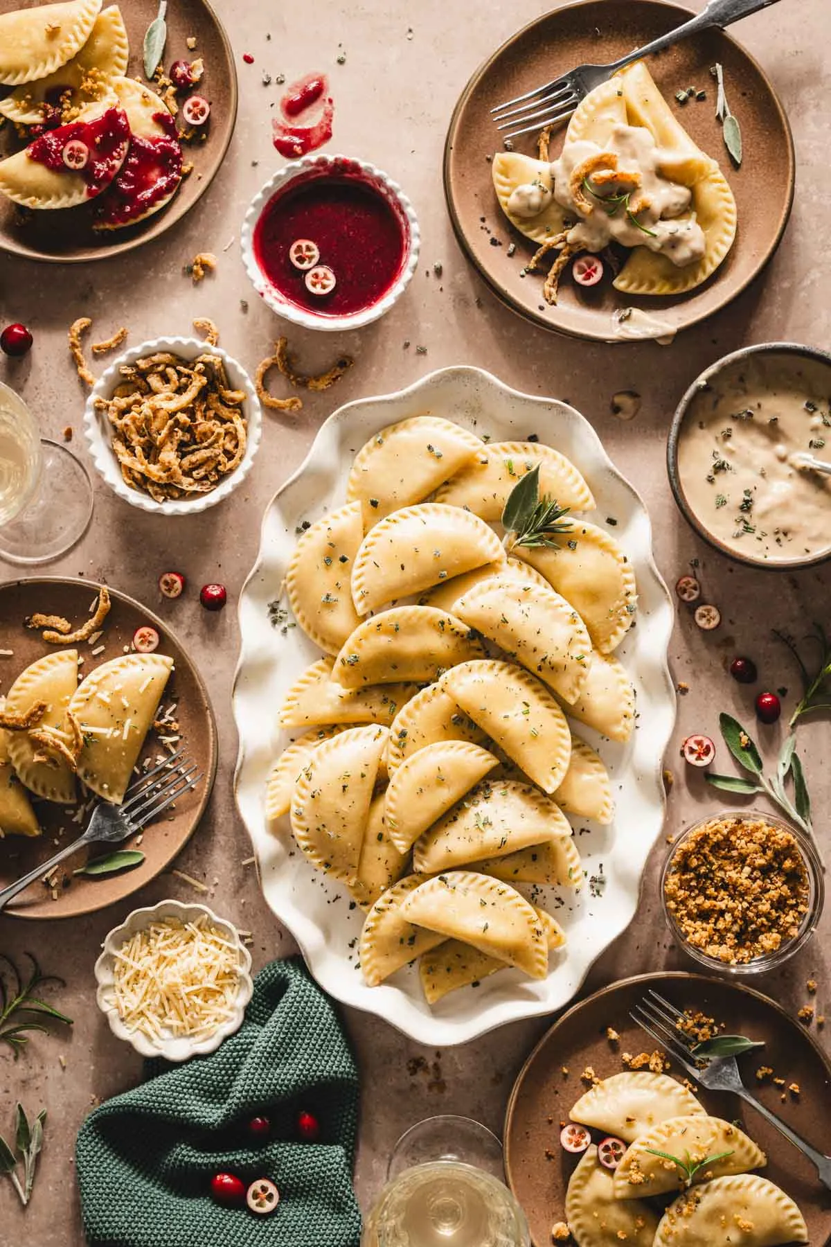 cooked pierogis on a serving platter, plates with pierogis, dished with gravy, sauce, cheese