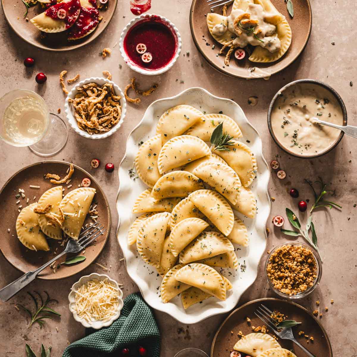 cooked pierogis on a serving platter, plates with pierogis, dished with gravy, sauce, cheese