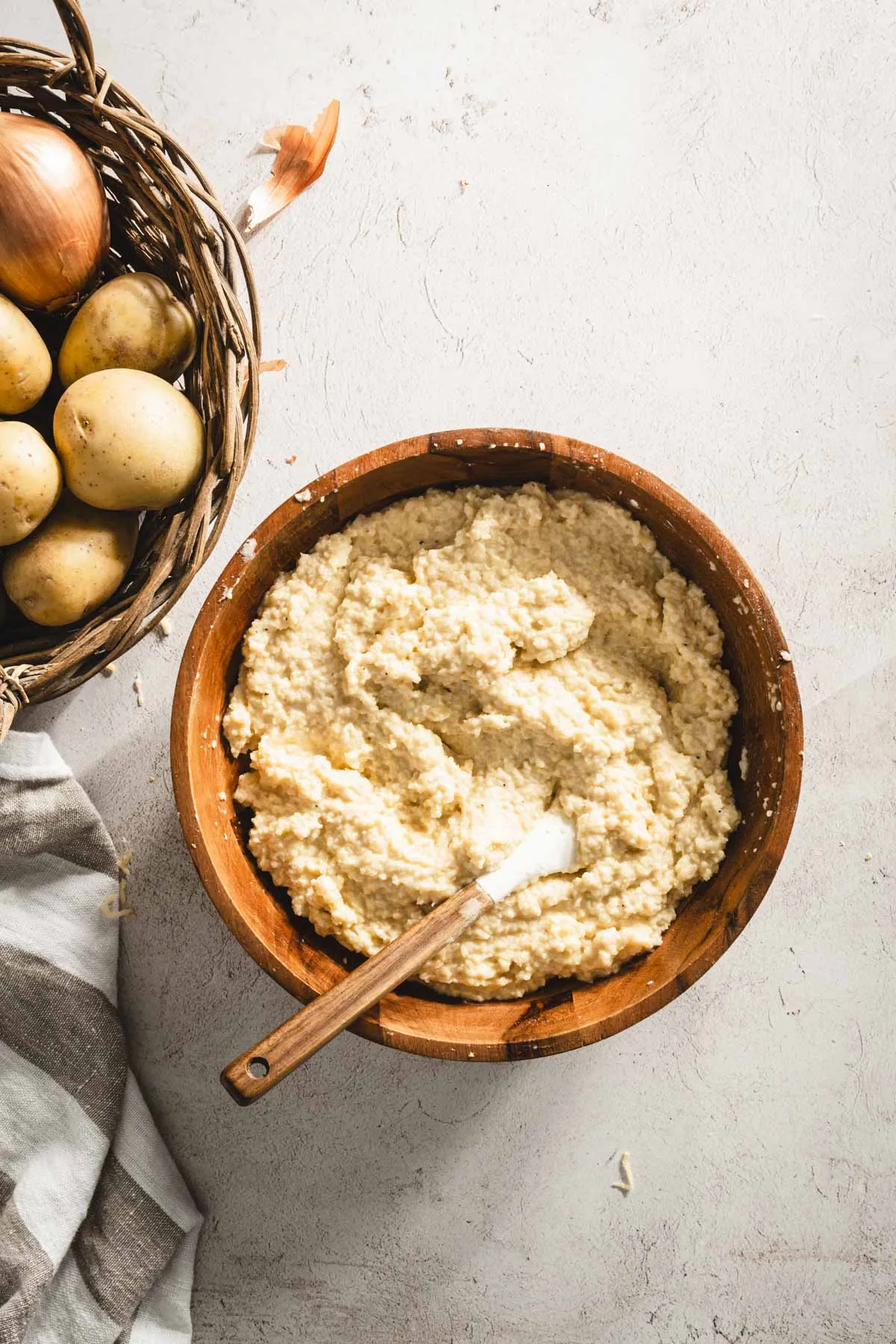 potatoes mixture all mixed in, spatula, basket with whole potaotes