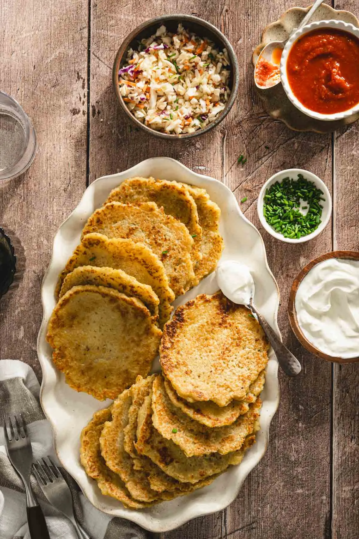 potatoes pancakes styled on a serving platter; small bowls and dishes with various garnishes