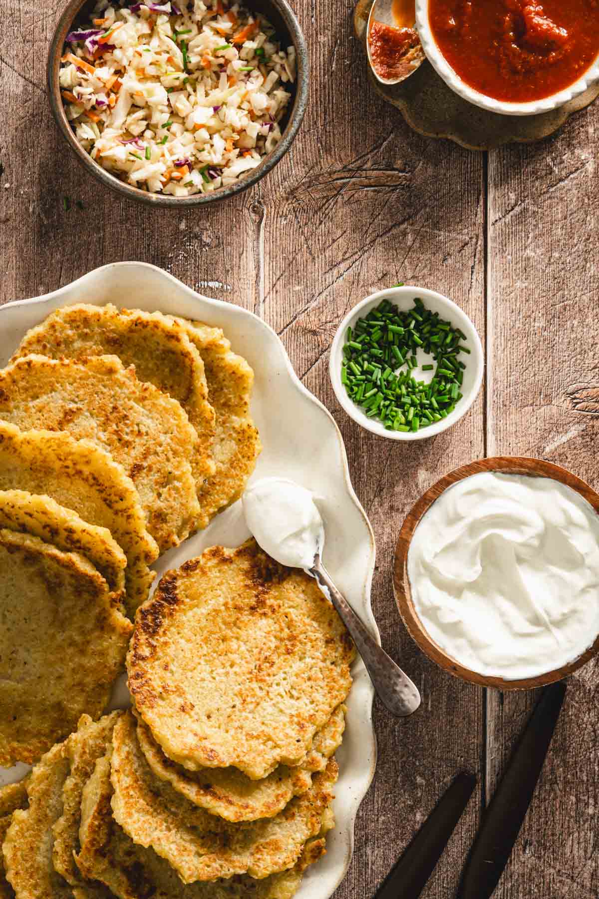 potatoes pancakes styled on a serving platter; small bowls and dishes with various garnishes