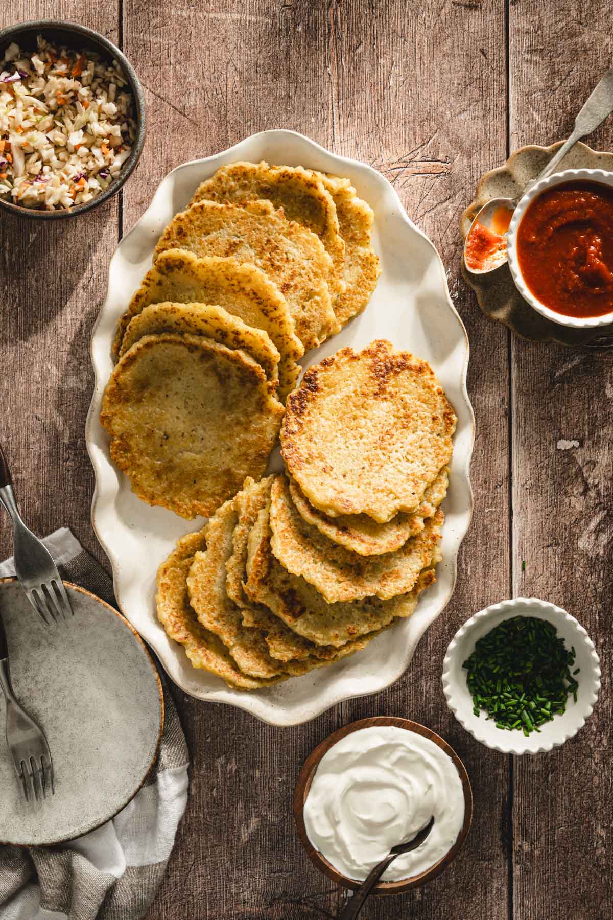 potatoes pancakes styled on a serving platter; small bowls and dishes with various garnishes