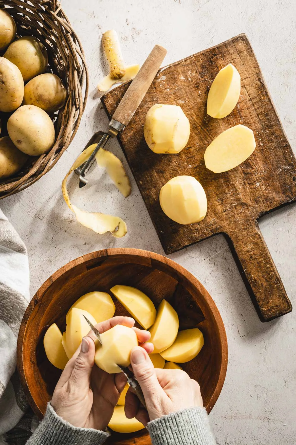 hands in frame cutting potatoes, cutting board, knife