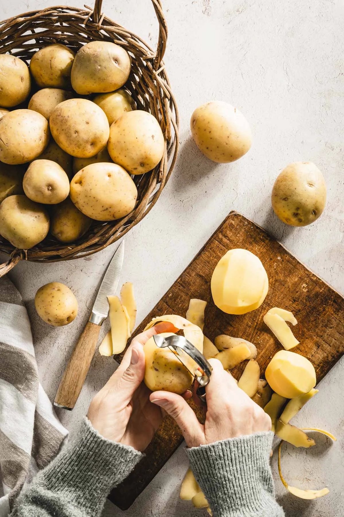 hands in frame cutting potatoes, cutting board, knife