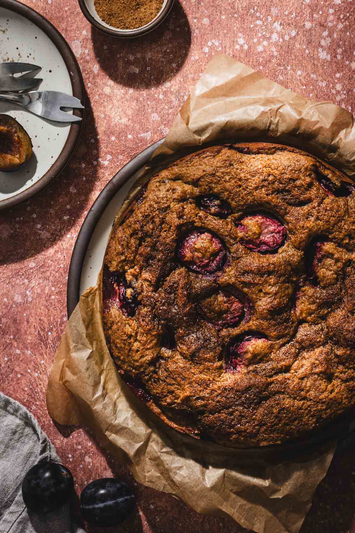 cake on a serving plate, small plates, fresh plums