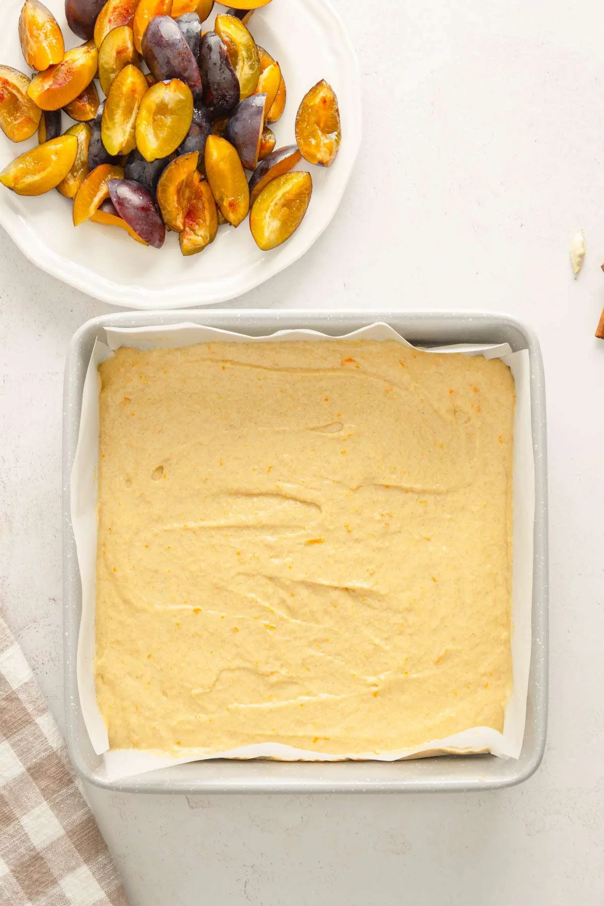 batter in a baking pan, dish with cut up plums
