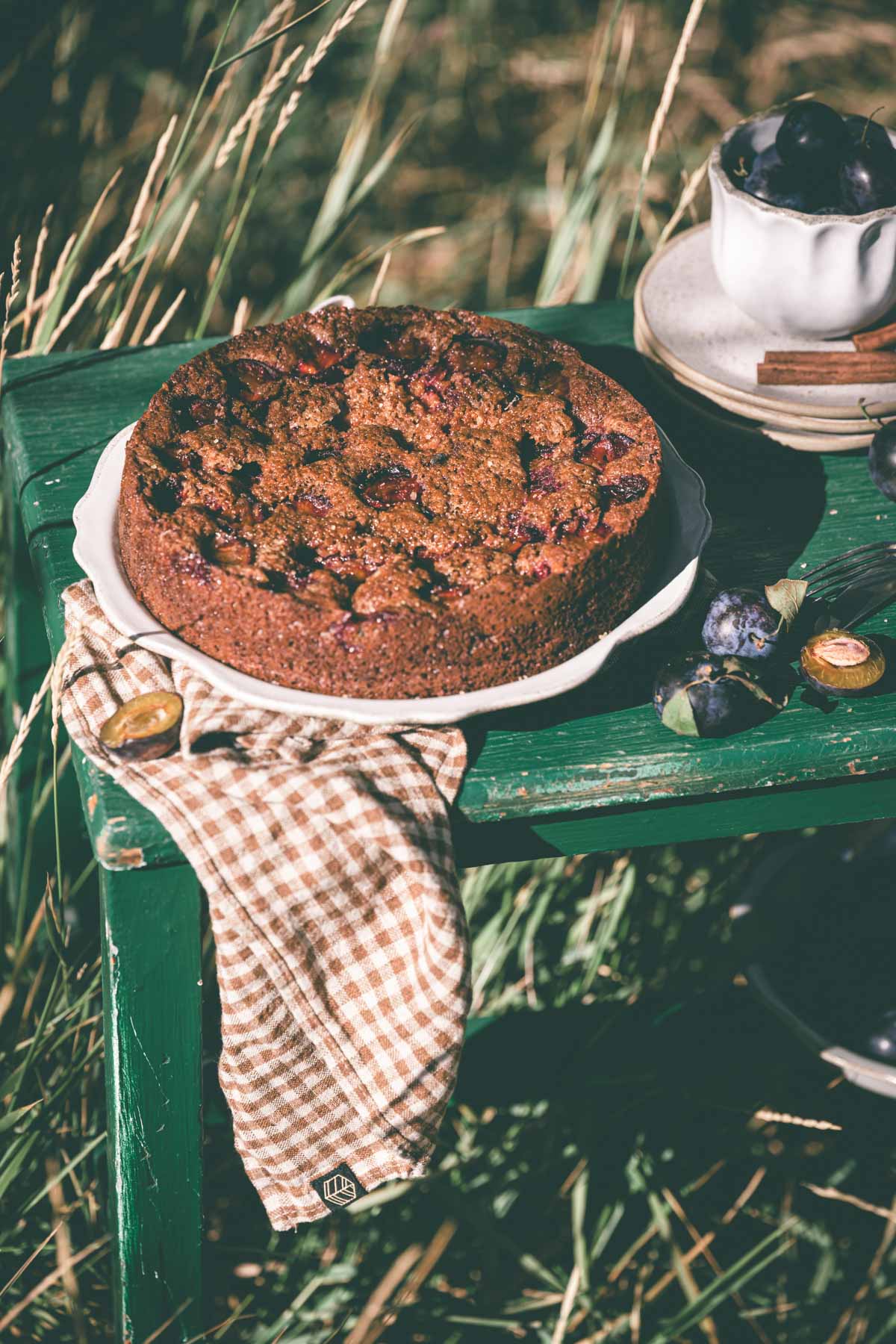 side view of a plum cake on aserving plate placed on a wooden table