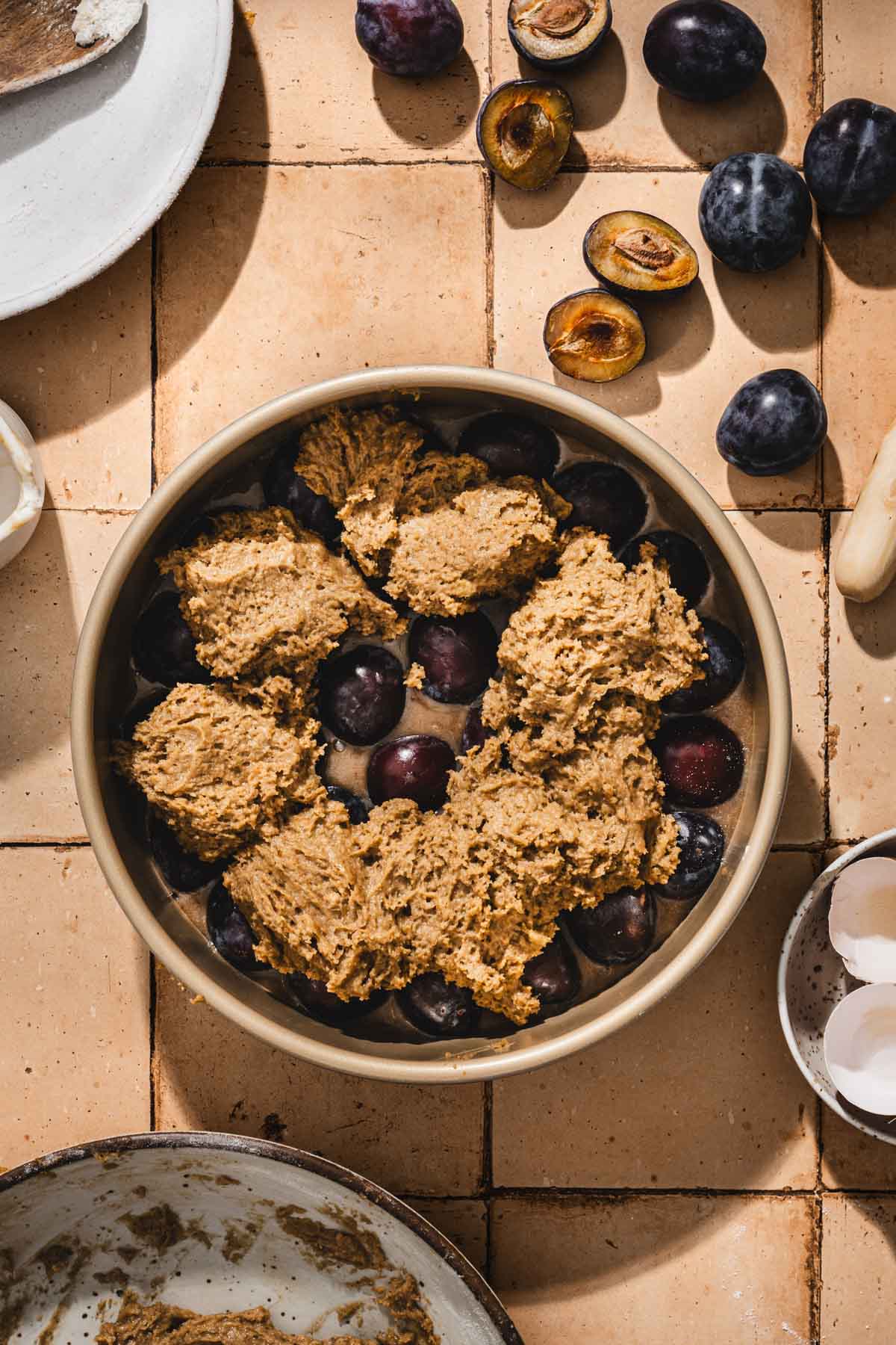 pan with plums arranged and batter on top
