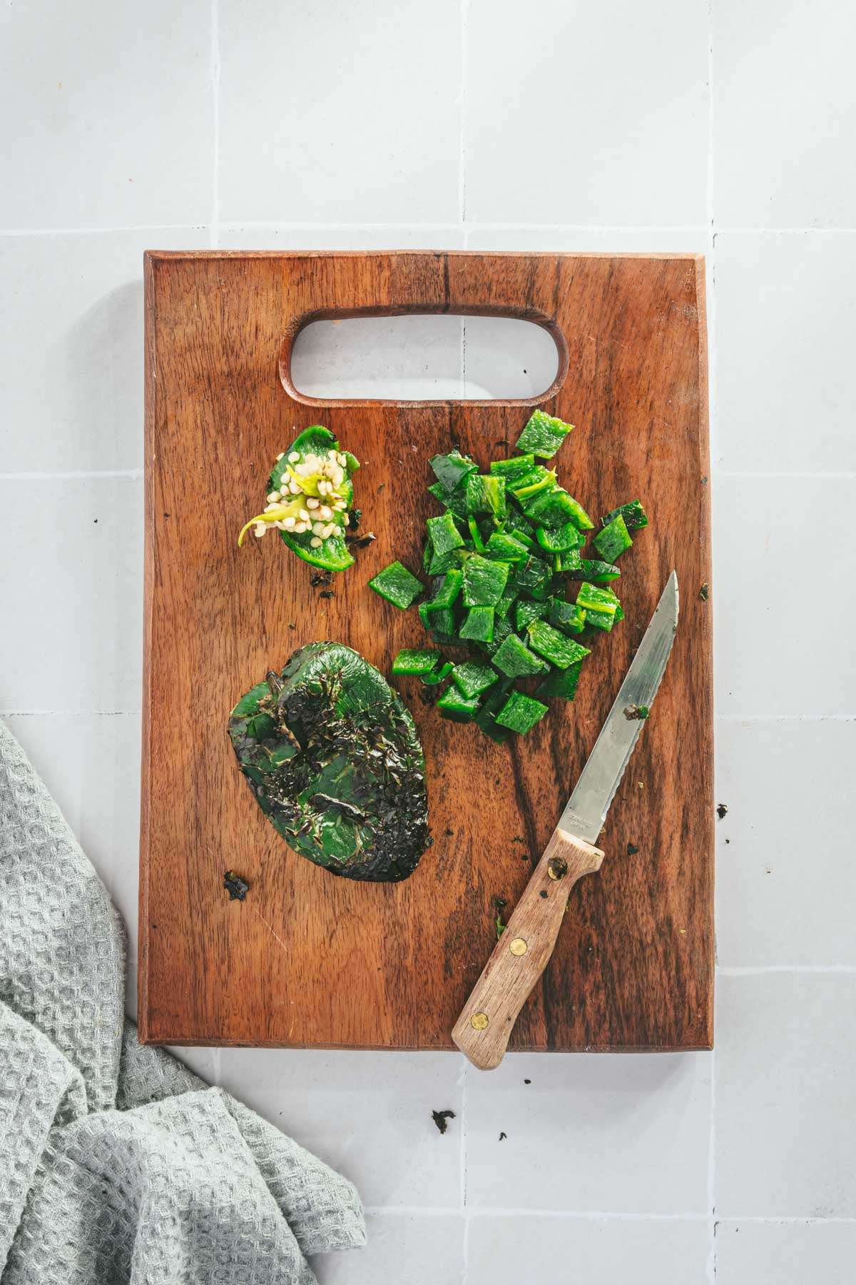 Roasted Poblanos(one chopped) on a cutting board, small knife