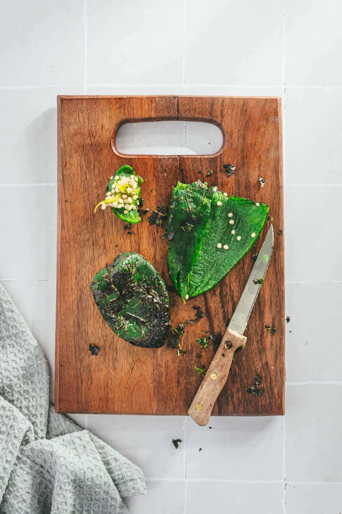 Roasted Poblanos (one cut open) on a cutting board, with knife