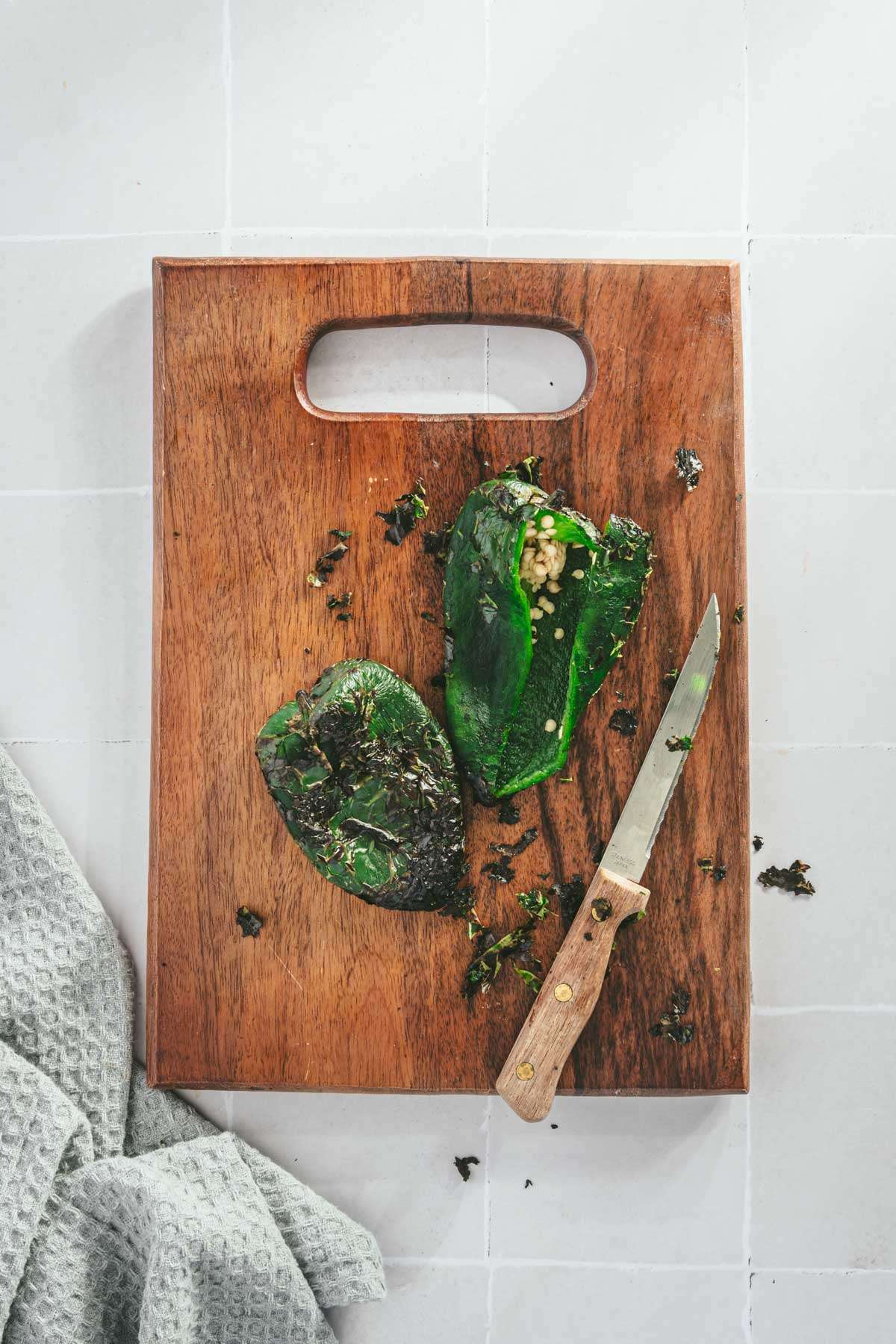 Roasted Poblanos (one cut open) on a cutting board, knife