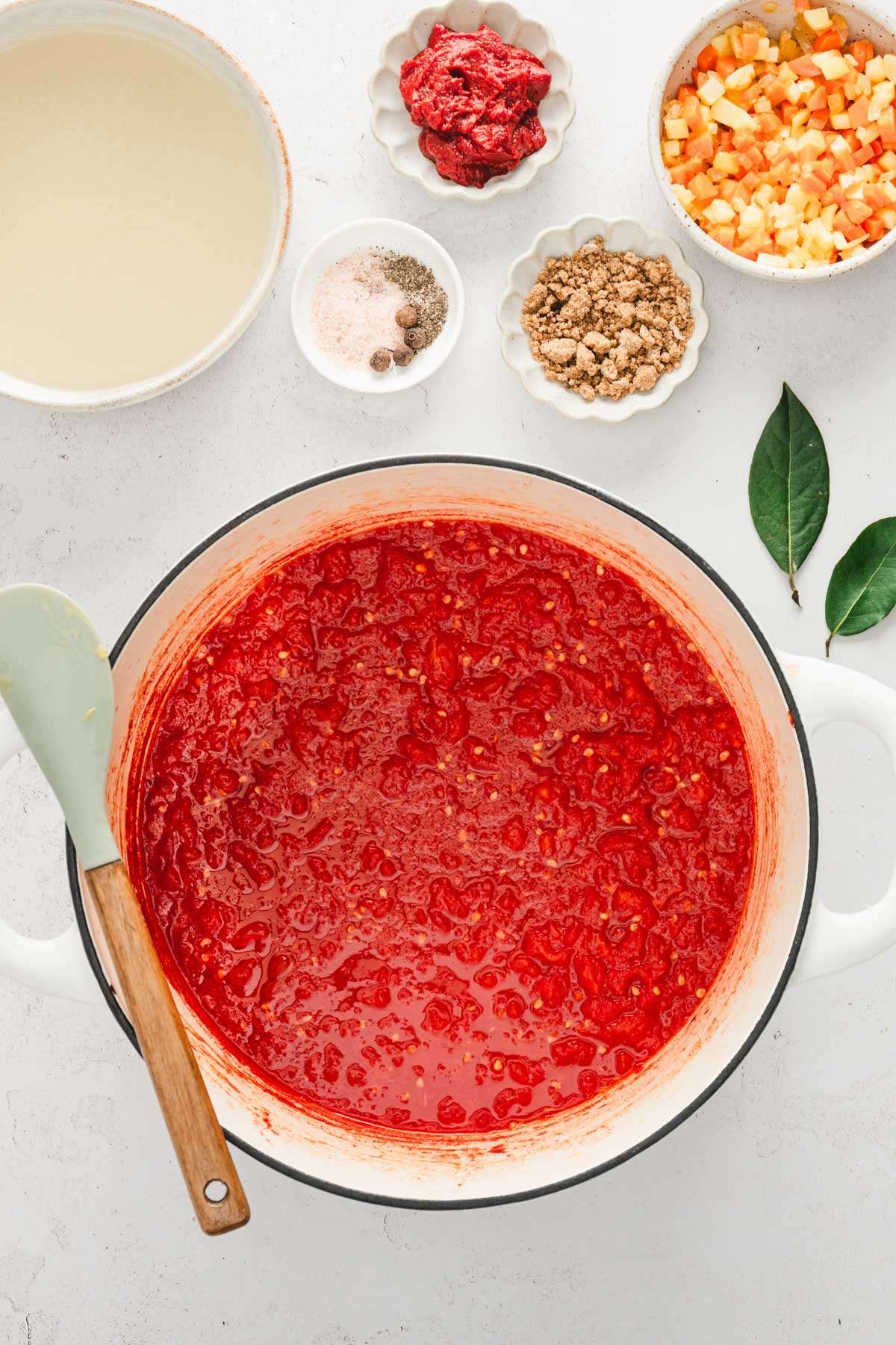 large stock pot with cooked down tomatoes, dish with broth, cooked veggies and aromatics