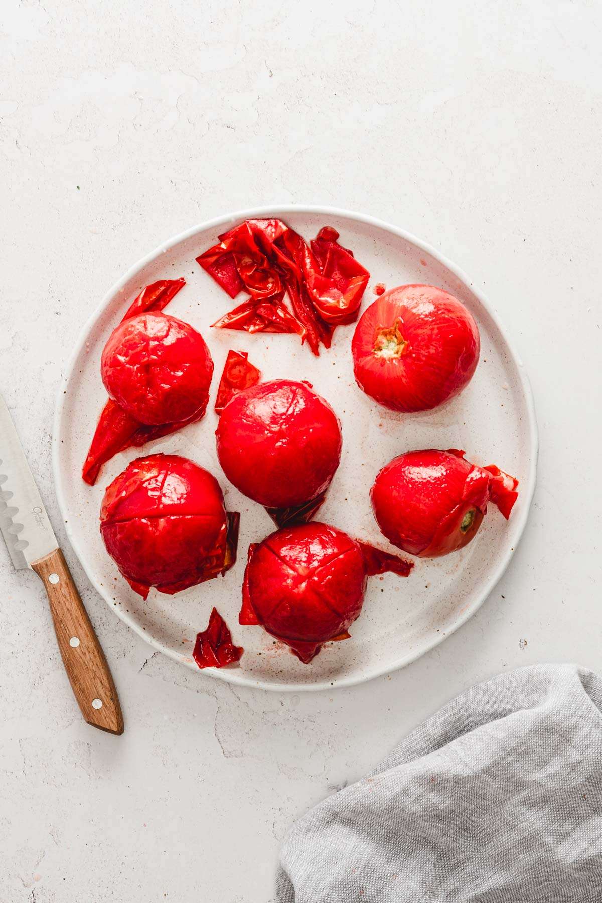 large plate with blanched tomatoes, partially peeled