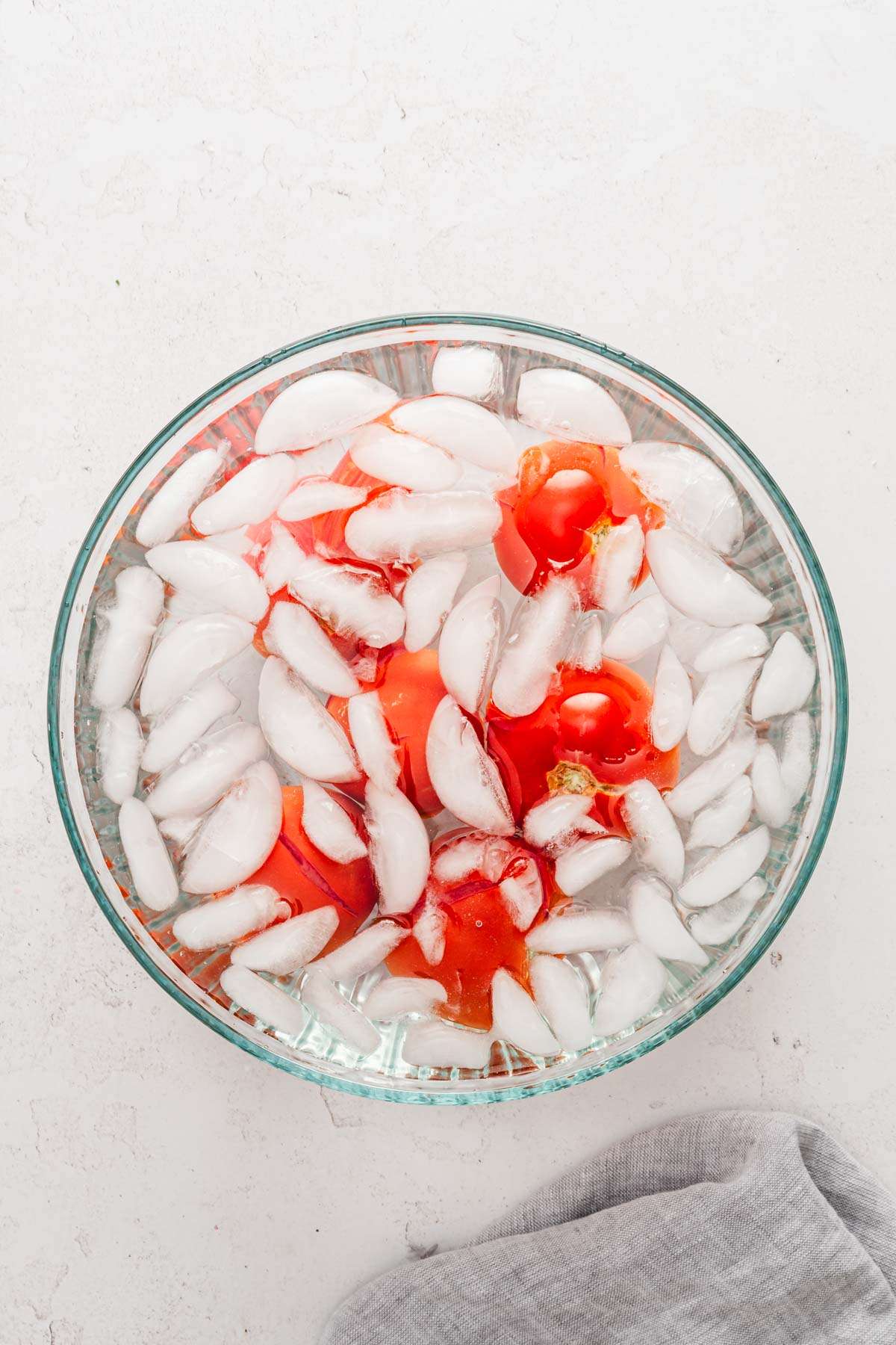 large glass bowl with water, ice and tomatoes