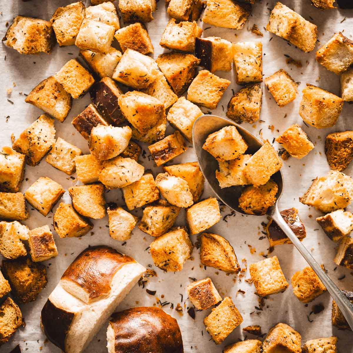 pretzel bun croutons on a baking sheet, spoon in frame