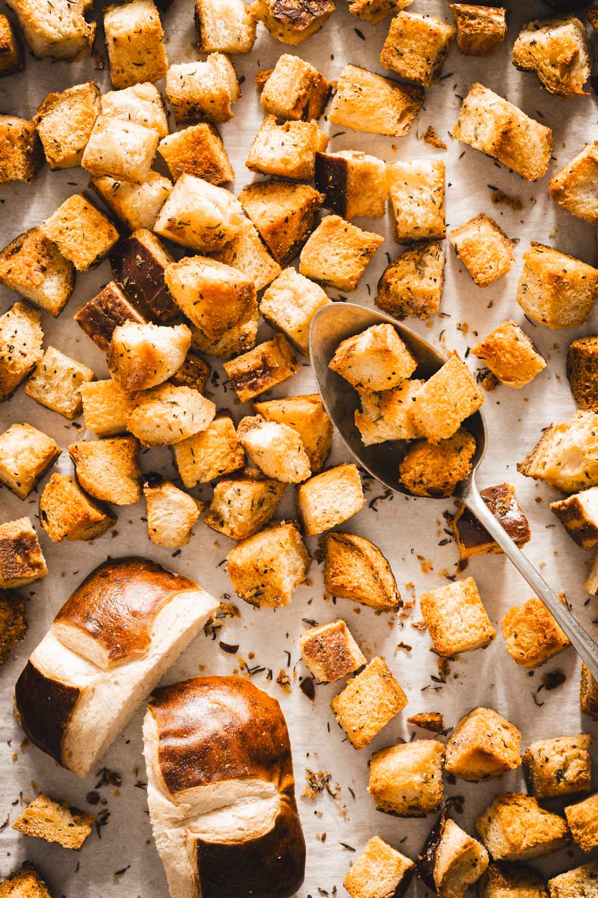 pretzel bun croutons on a baking sheet, spoon in frame