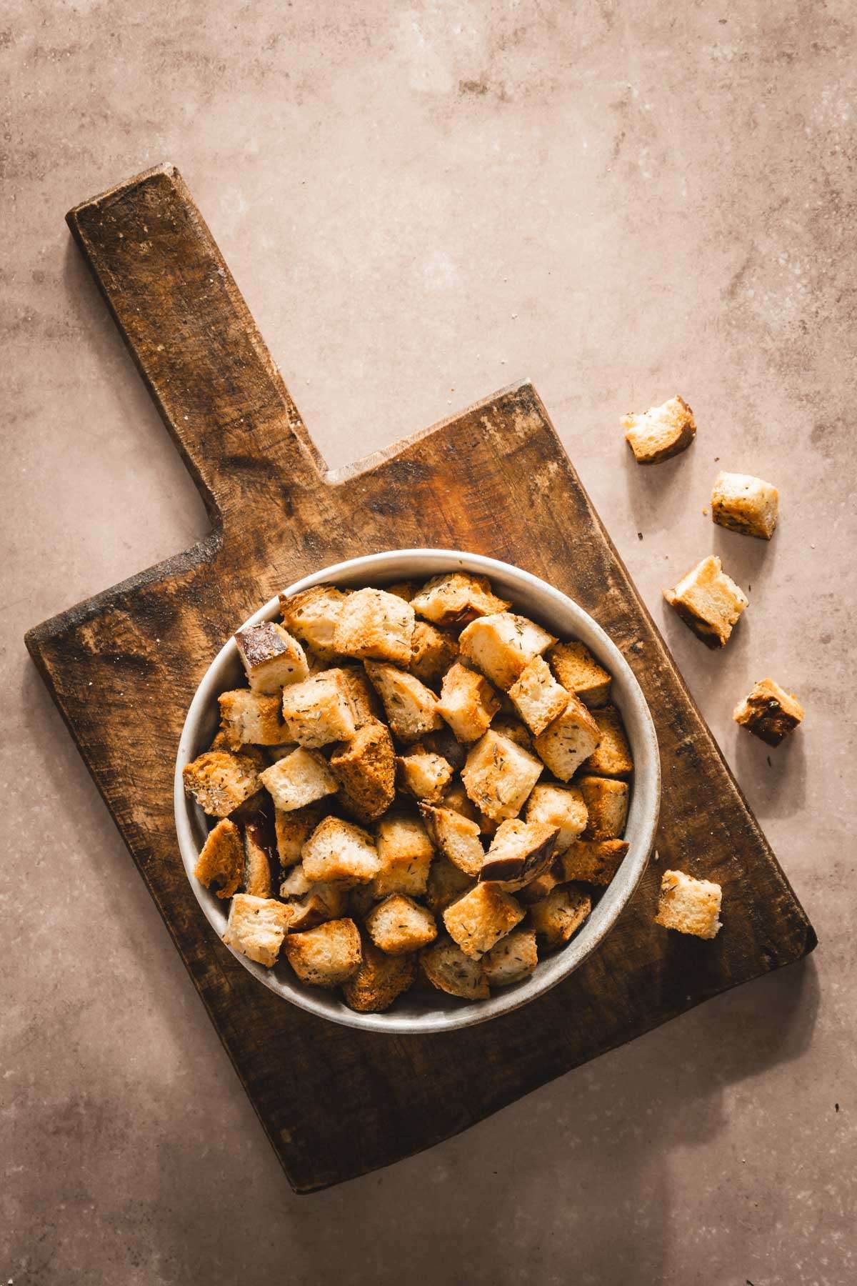 pretzel bun croutons in a serving bowl on a wooden cutting board