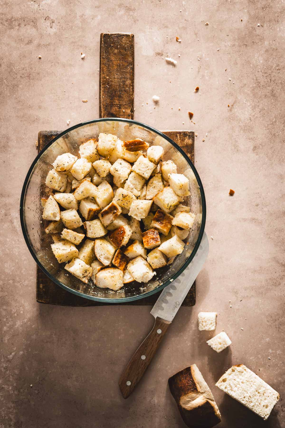 large glass bowl with cut up pretzel buns, added olive oil